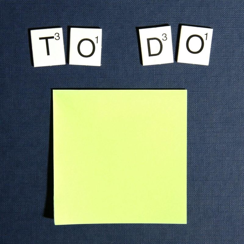 A blank sticky note displayed under scrabble tiles spelling 'To Do' on a blue background.
